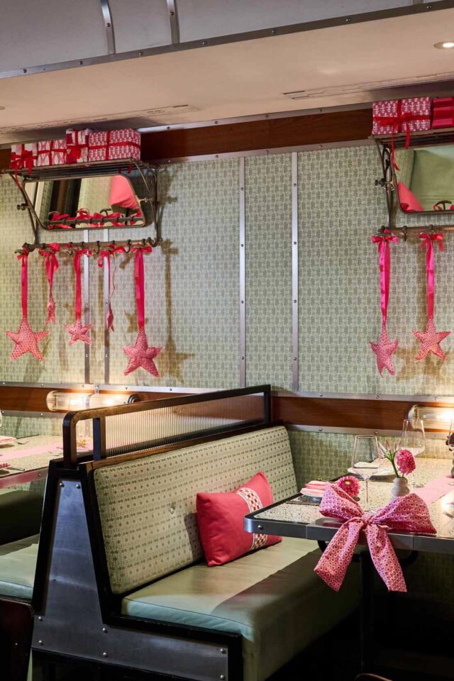 Guests dining inside the festive Winter Carriage train setup at Bombay Bustle London.
