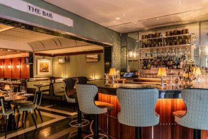 The elegant bar, featuring rich jacquard and leather stools set against vintage railway-inspired.